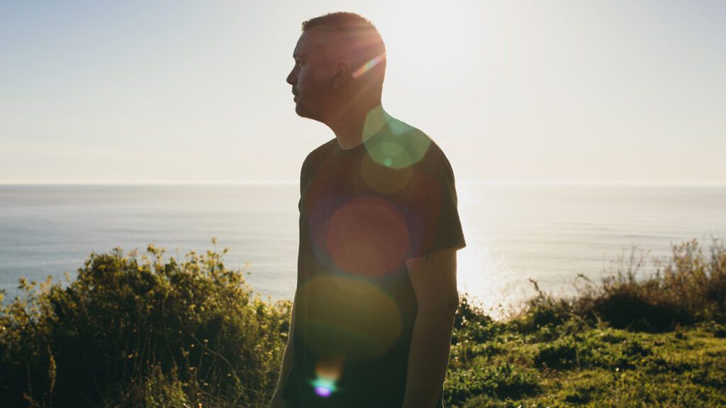 Man looking out into ocean in sunlight