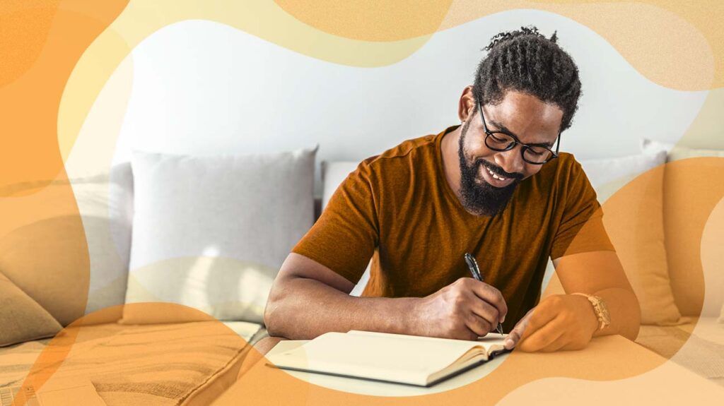 a man sitting on couch writing and smiling -2