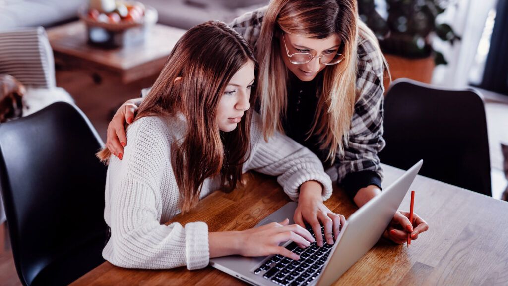 Mother and daughter looking at online therapy options on a laptop