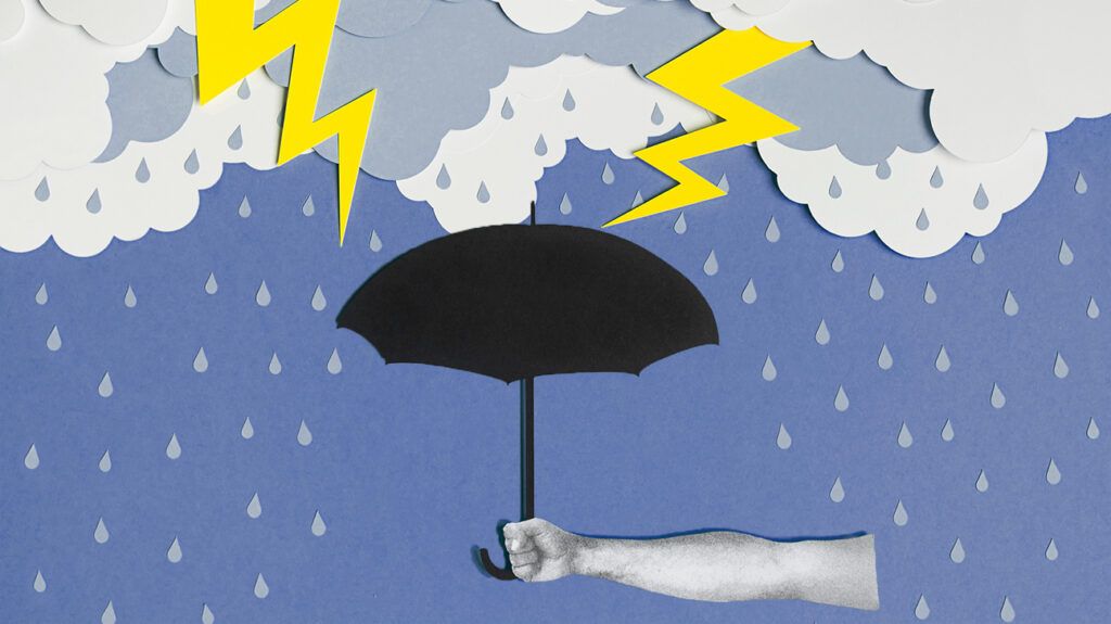 Paper cut scene of lightning storm over arm holding an umbrella