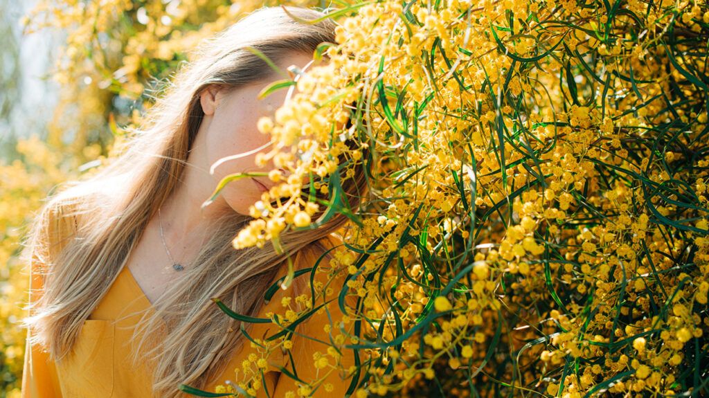 Woman hiding behind yellow flower bush