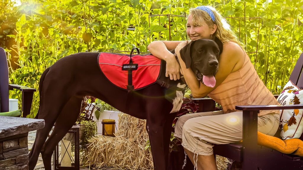 Woman who has bipolar disorder, embracing her psychiatric service dog that wears a vest