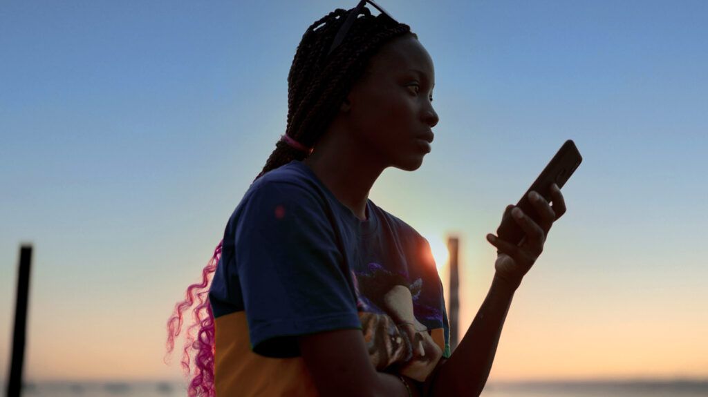 Young woman looking at her smartphone at sunset
