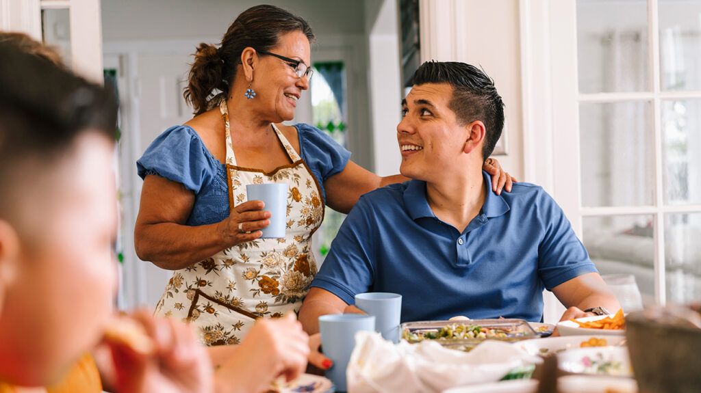 Around kitchen table, relative with an arm around family member who has depression