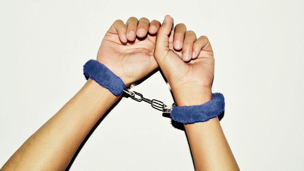 Hands bound with fuzzy blue soft handcuffs