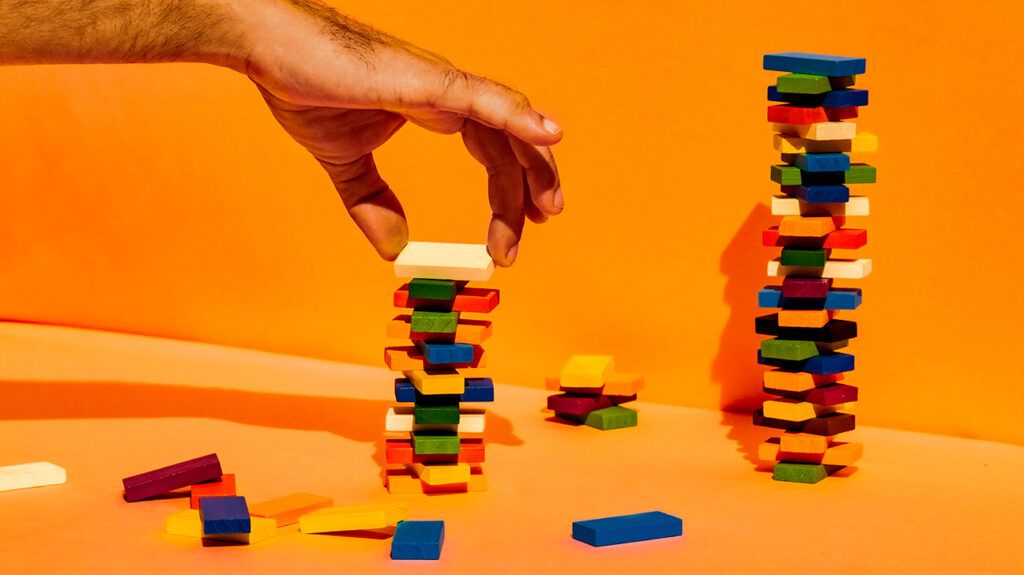 Man stacking building blocks against orange background