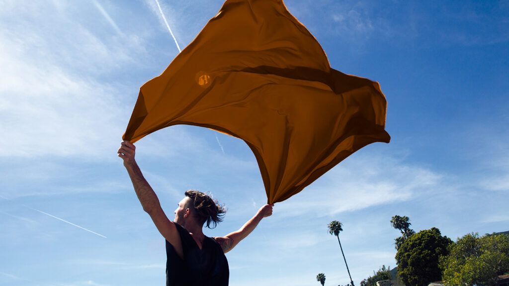 Man holding fabric toward the sky like a parachute, enjoying feeling of letting go