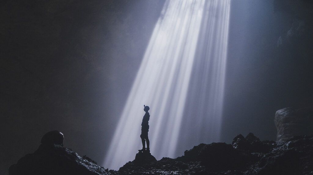 Man standing in a cave with sunbeams