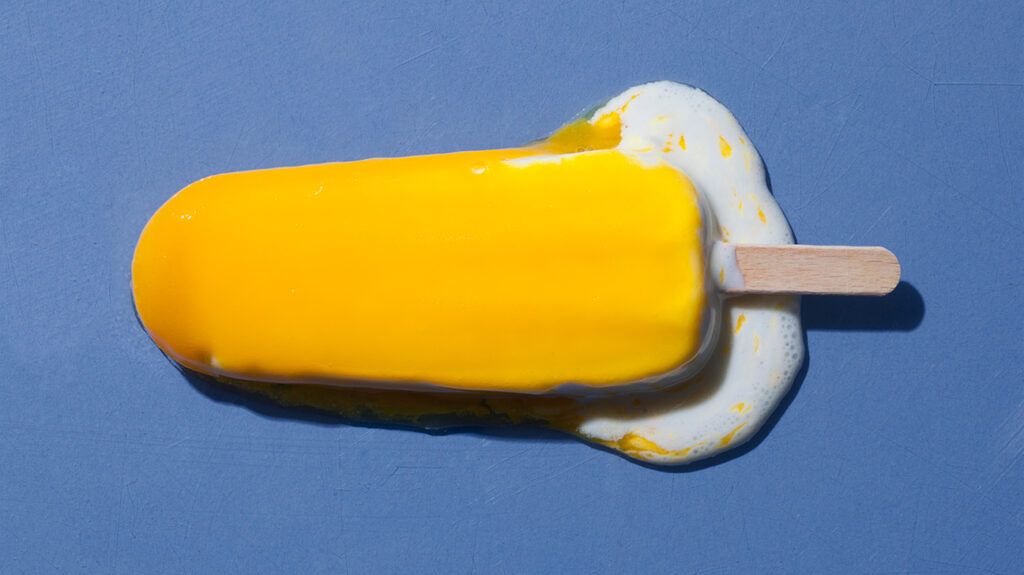 Yellow melting popsicle ice cream on a blue background