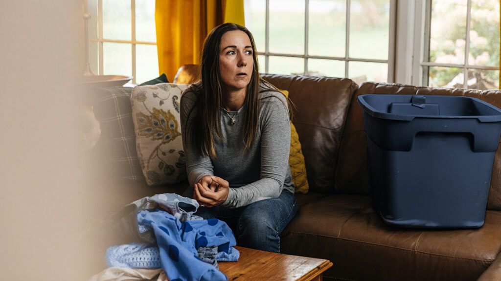 Thoughtful, sad woman sitting on living room sofa