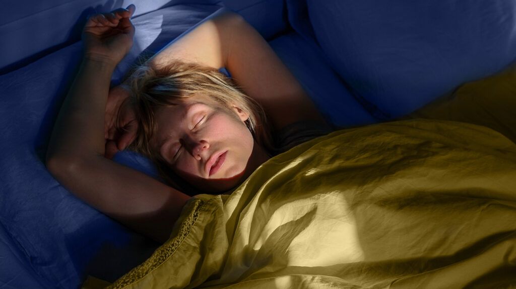 Woman sleeping in bed with sunlight on her face