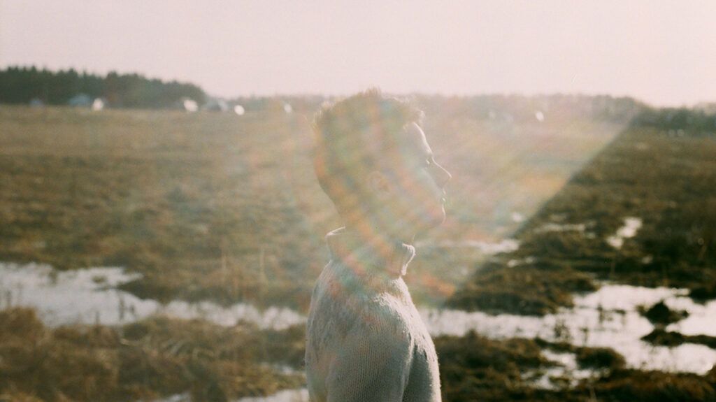 Young man standing outdoors in sun flare