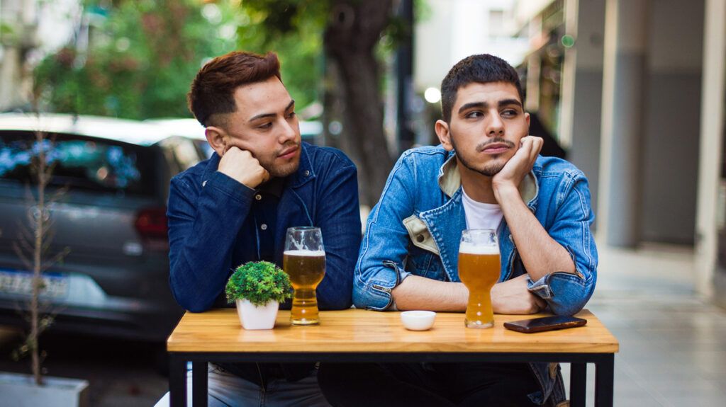 One friend using his expression to lay a guilt trip on the other, both with their hands on their chins