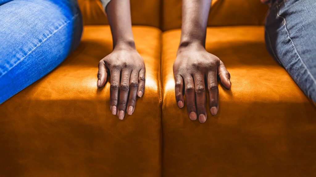 Couple with hands on couch not touching