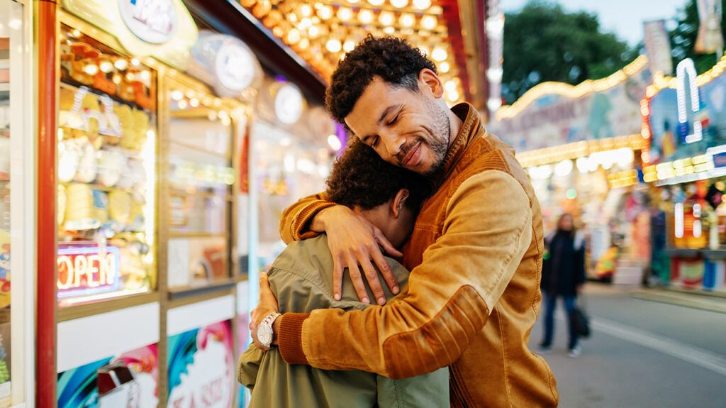 Father embracing son, who's become emotionally dysregulated at county fair.