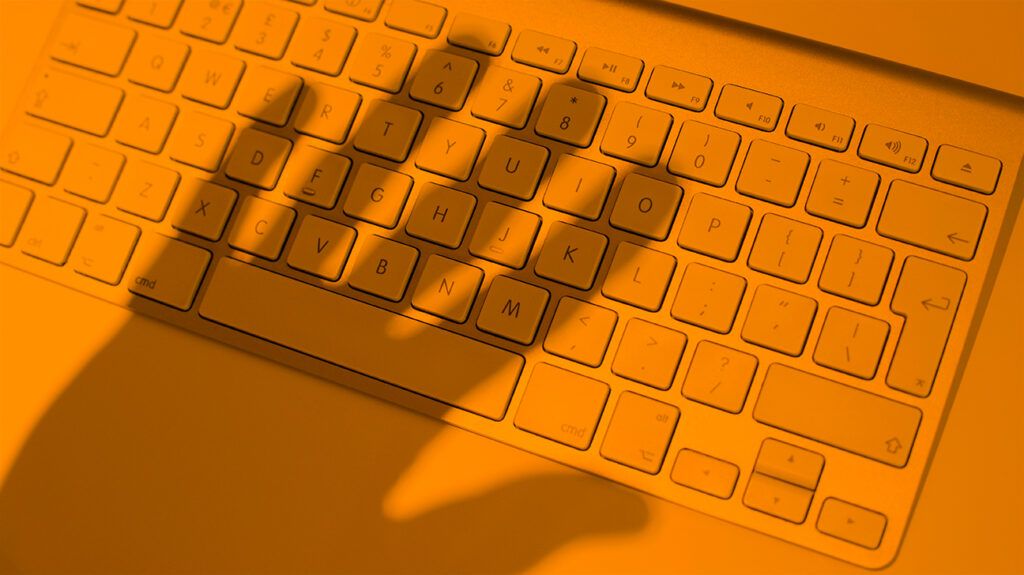 Person's hand looming over keyboard about to continue sexual bullying on social media