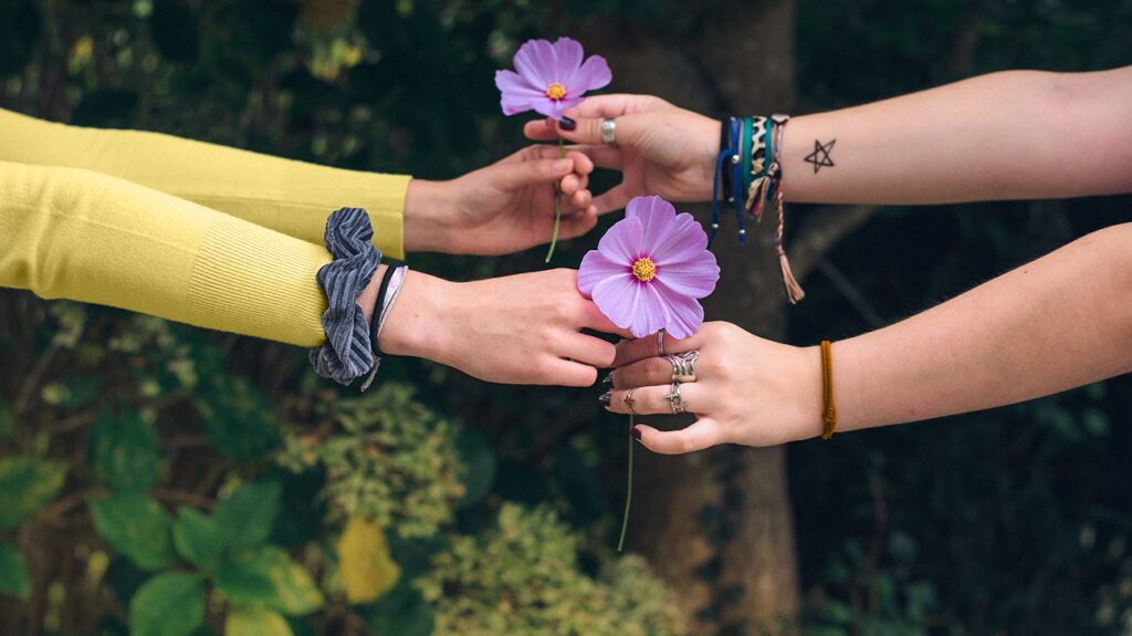 Hands and arms of friends giving flowers