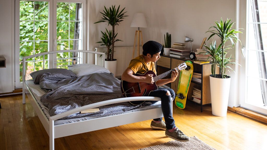 man playing guitar in bedroom