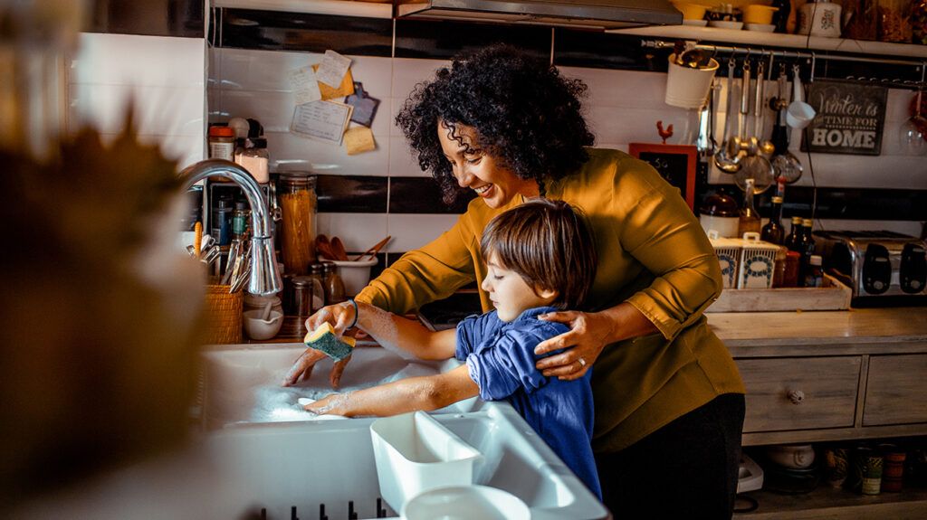 Mother using authoritative parenting to guide son in doing dishes