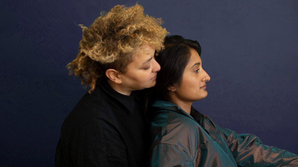 queer couple embracing on a greenish blue background