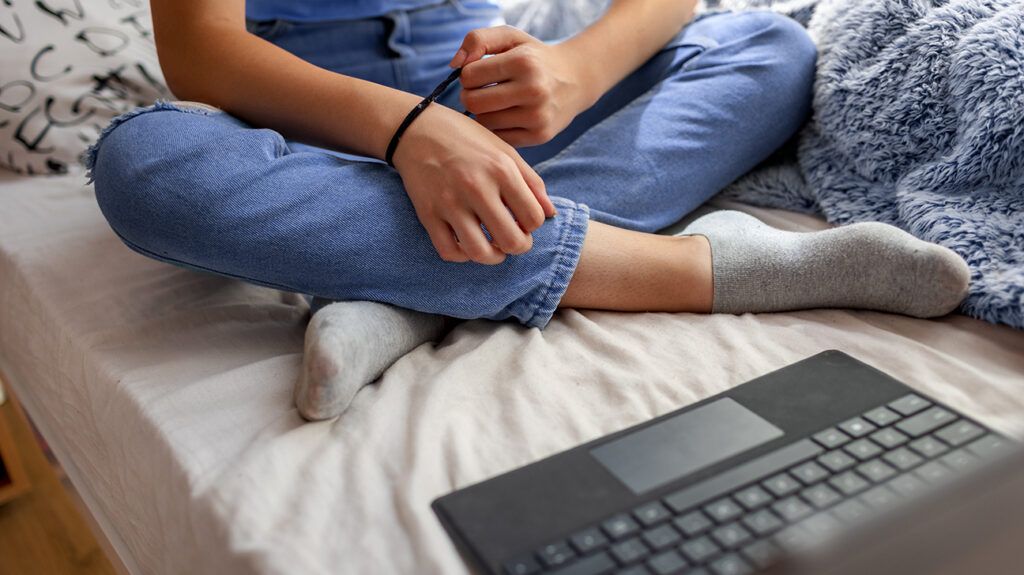 teenage girl sitting on bed video call laptop 1296x728 header