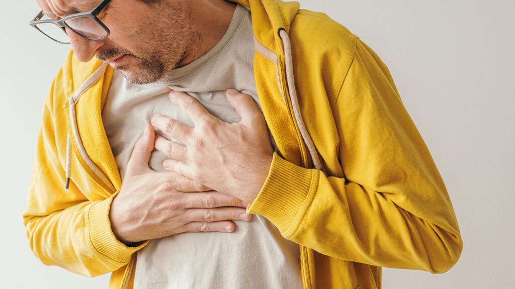 A man holding his chest experiencing pain and discomfort