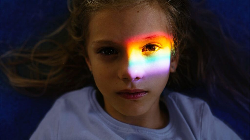 Young child with rainbow light shining on face