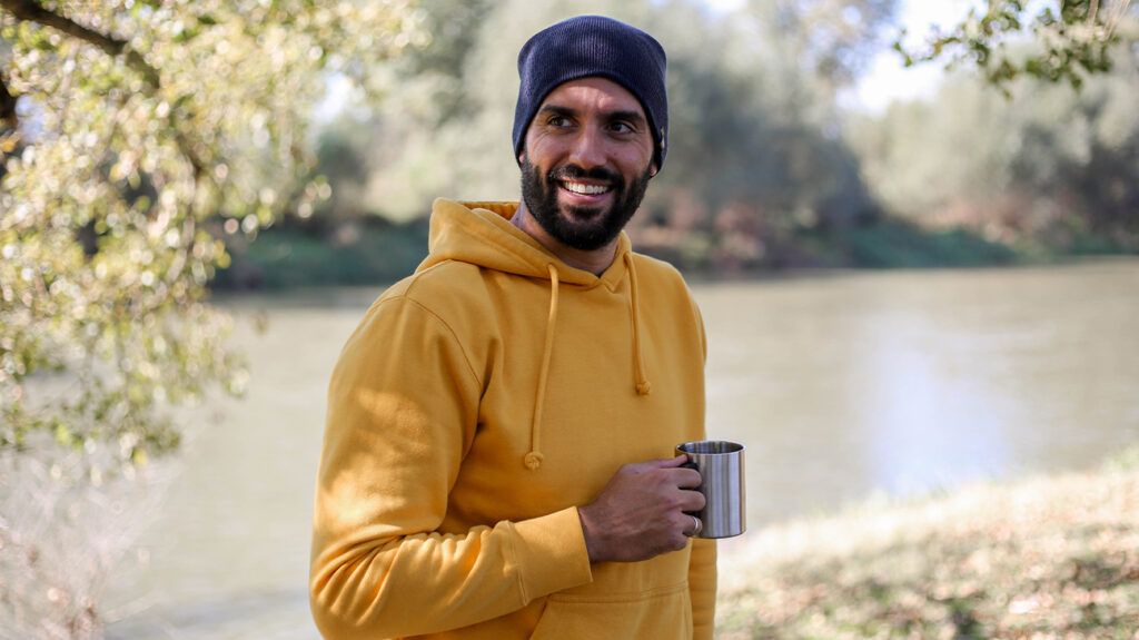 Man standing by the river with coffee cup