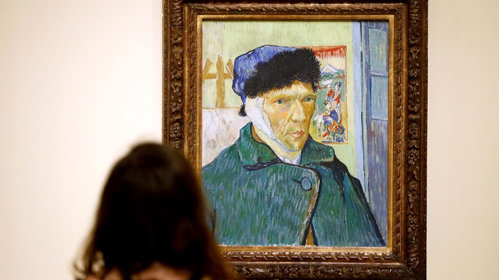 Woman standing in front of Vincent van Gogh self-portrait at museum