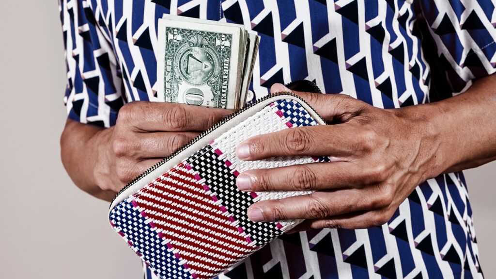 Close up image of a person holding a wallet and dollar bills
