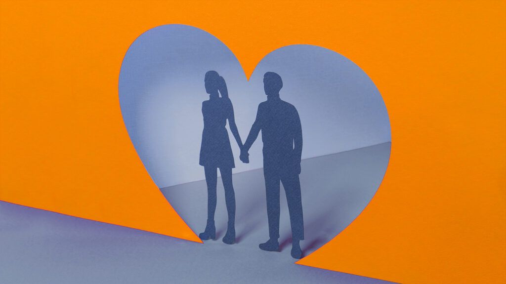 paper cut out of a couple holding hands in a heart shape