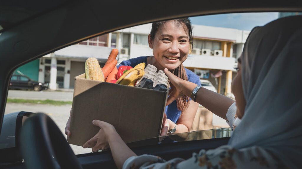 Woman handing out a box with food in an example of altruism