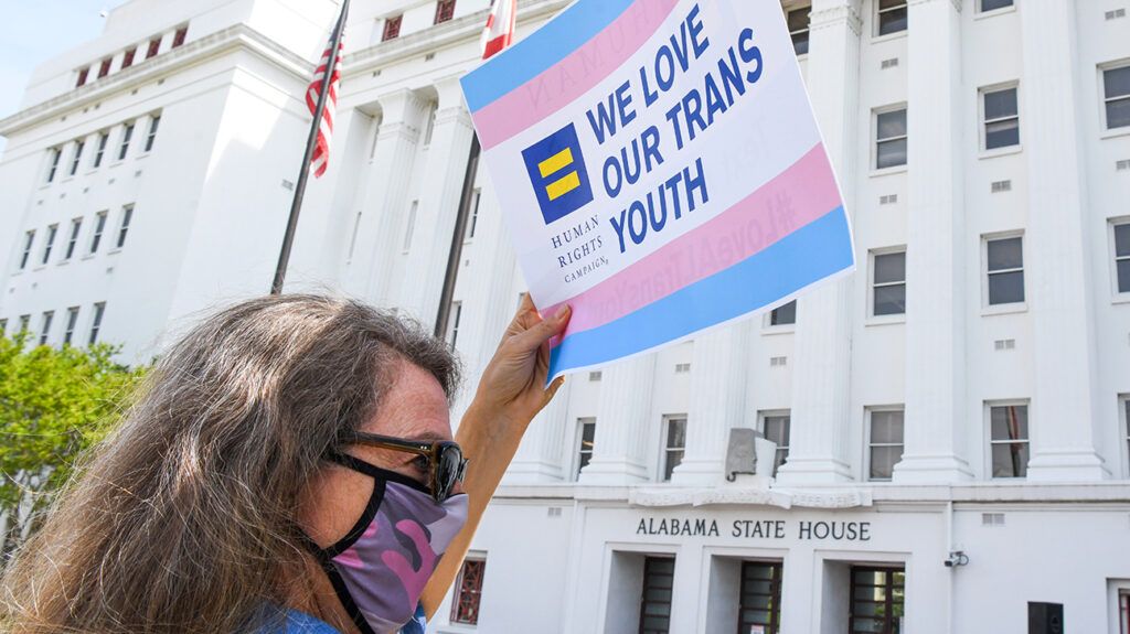 woman holding trans youth sign in alabama