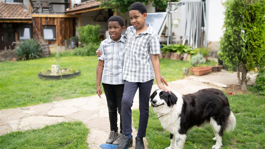 brothers standing together outdoors with pet dog