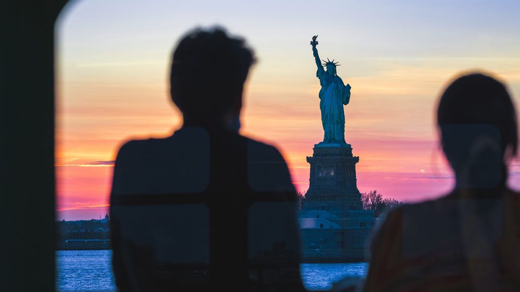 Silhouettes of person with depression looking at statue of liberty, wanting to immigrate to United States