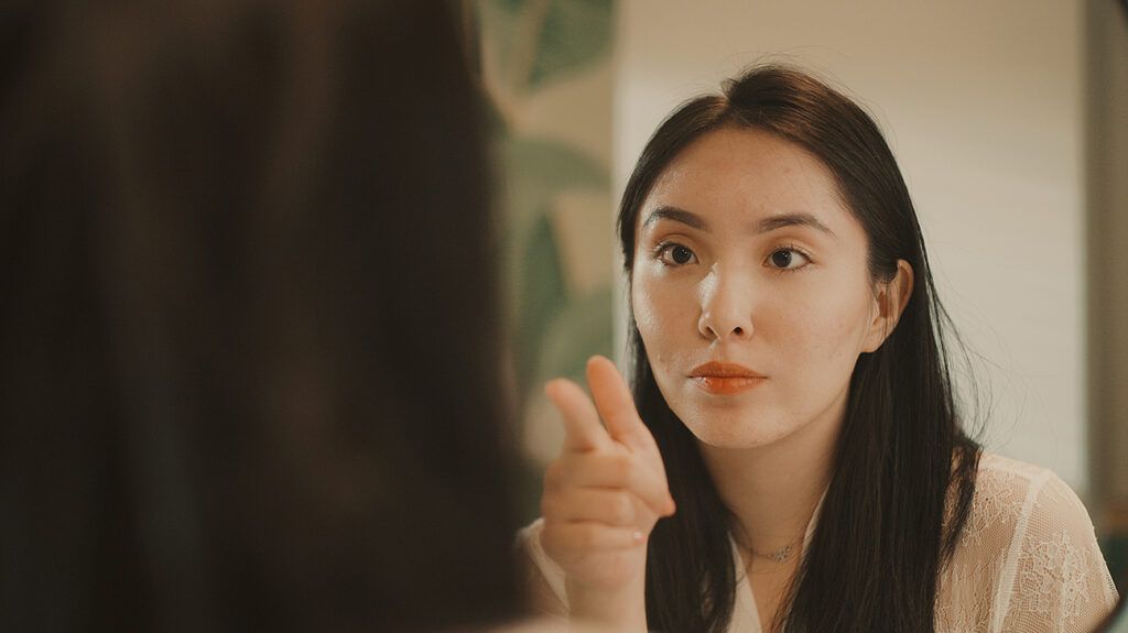 Woman pointing at self in mirror