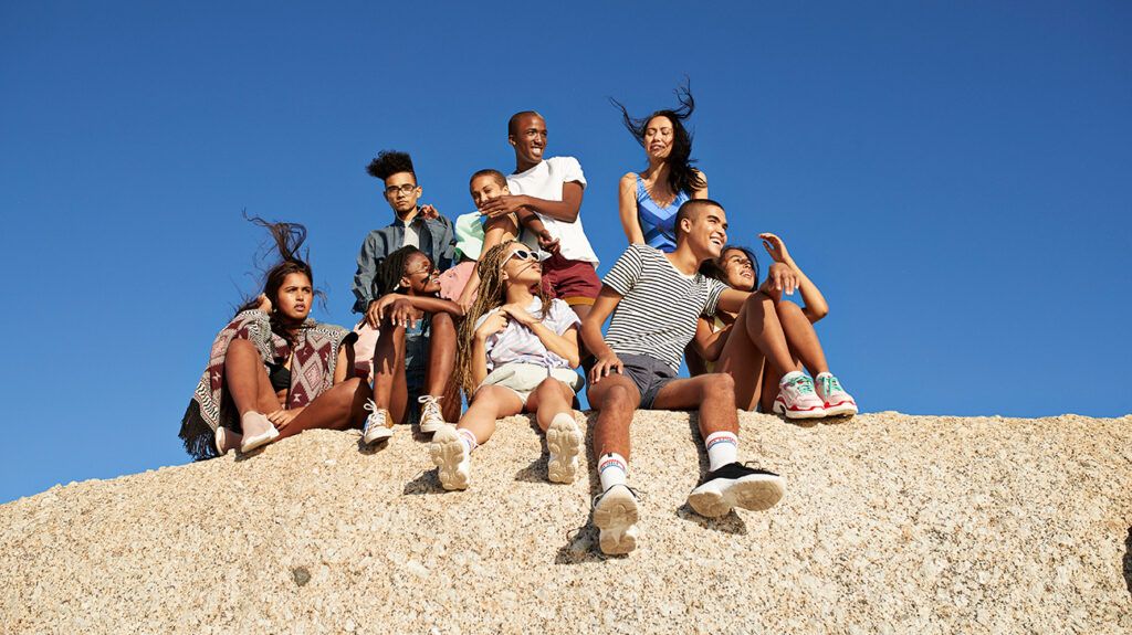 a diverse group of friends sitting on a large rock