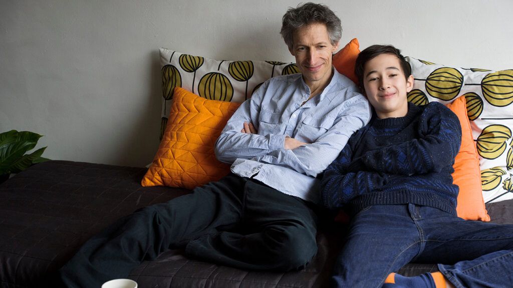 Father and teen son relaxing shoulder to shoulder on couch