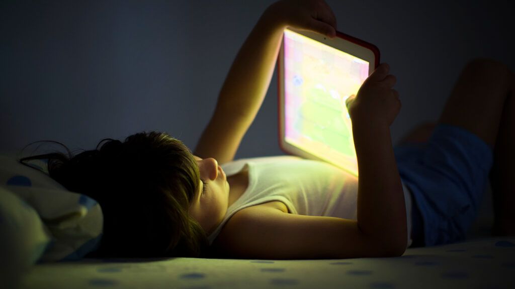 kid with adhd using a tech screen in the dark