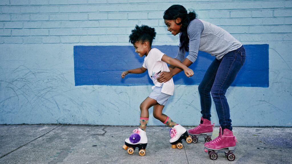 Mom helping her daughter rollerskate, in a lesson of emotional resilience