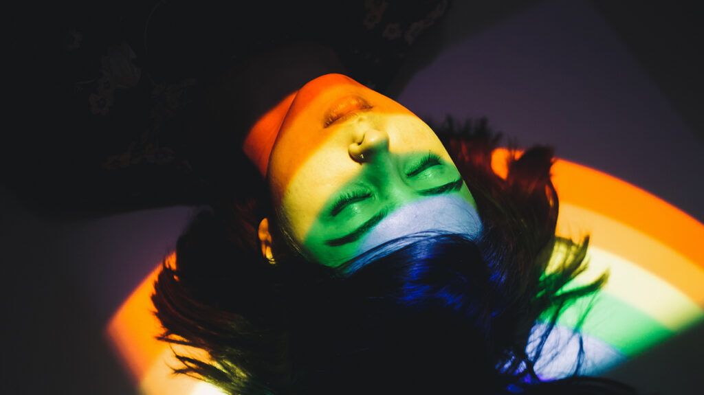 Person lying on floor with rainbow reflection, symbolic of myriad of emotions