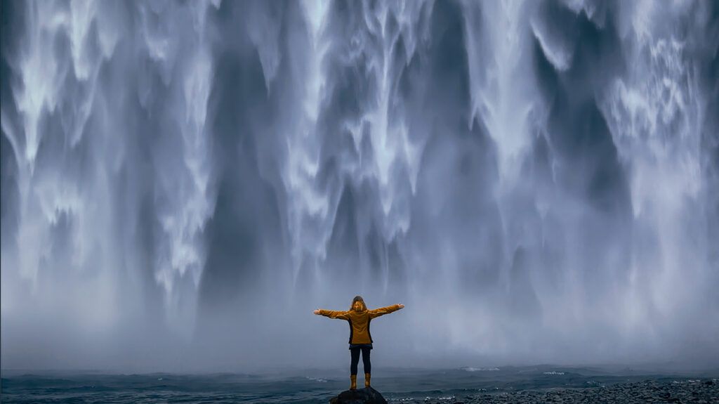Person standing under a waterfall, symbolic of emotional resilience and withstanding pressure