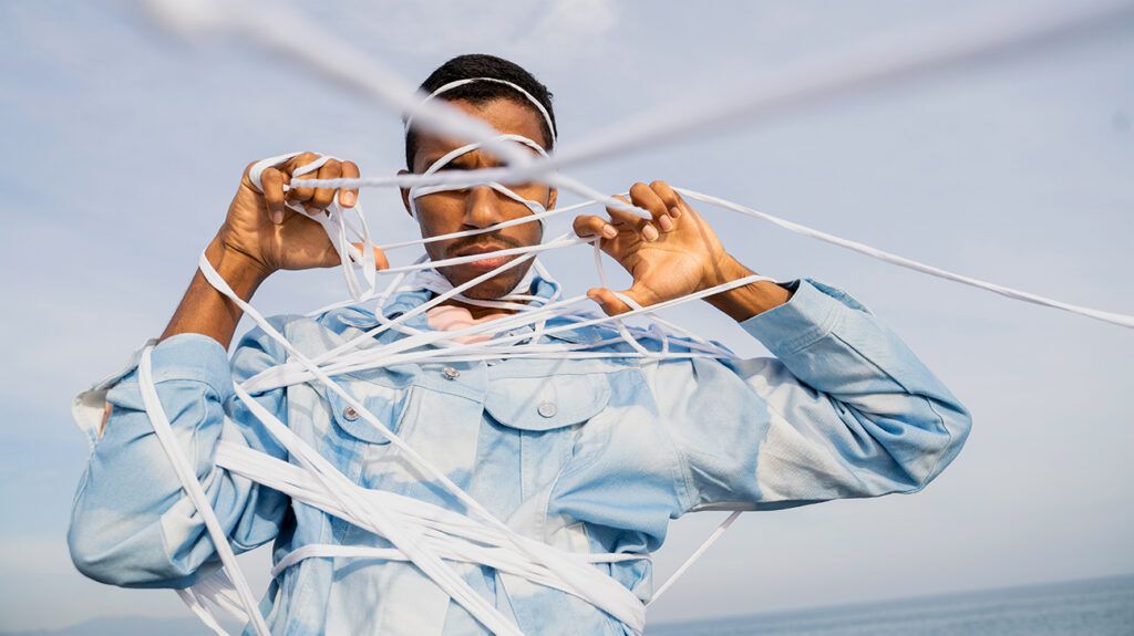 young man tangled in white ropes