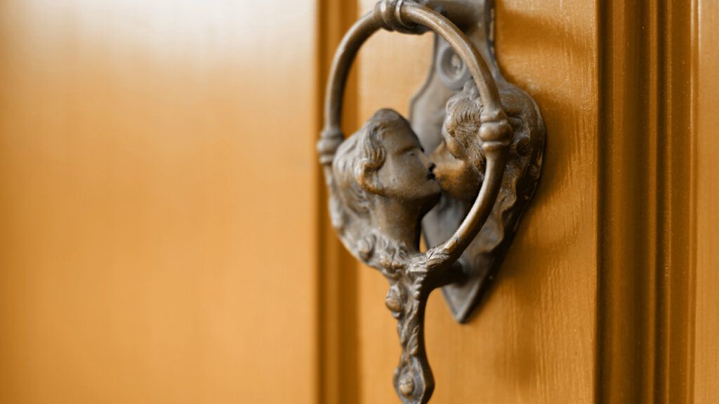 Closed house door with knocker of two faces kissing