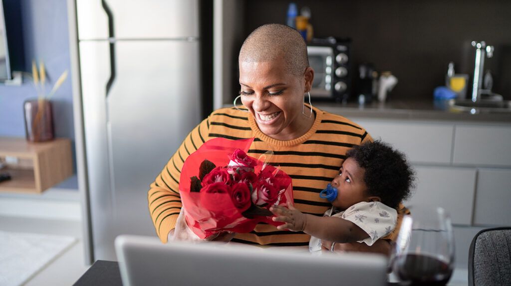 Single mom holding baby, admiring flower bouquet from a suitor