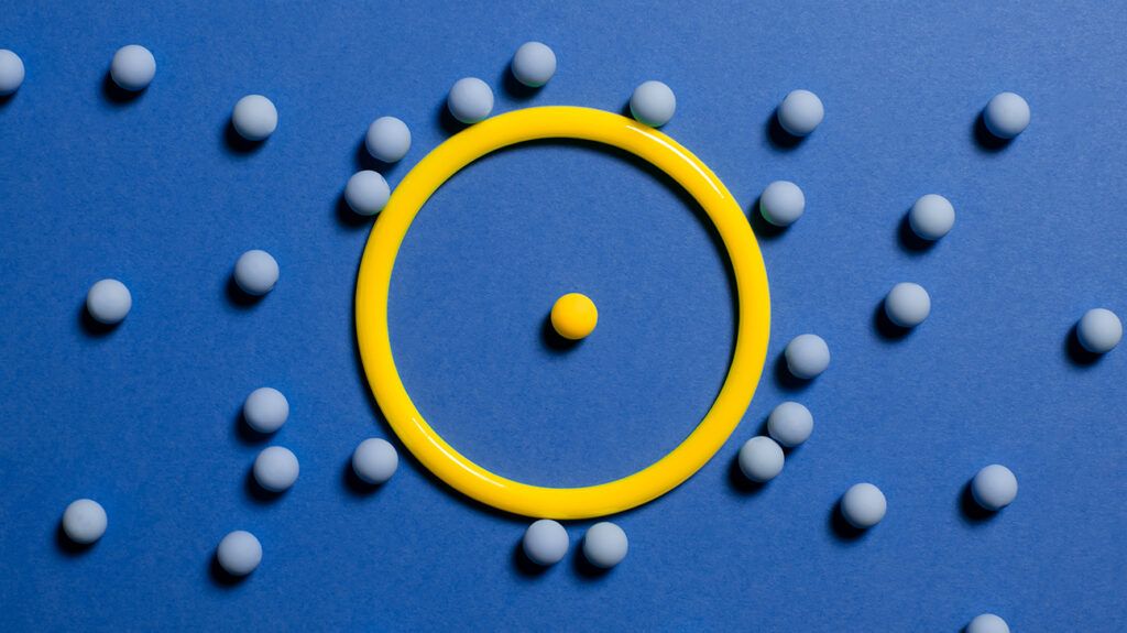 yellow ball in ring surrounded by blue balls