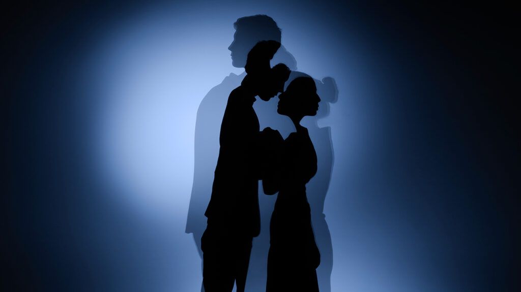 Husband and wife silhouette embracing, double exposure, husband turned away in second exposure