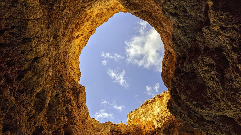 view looking through a hole in the ground showing clouds in the sky