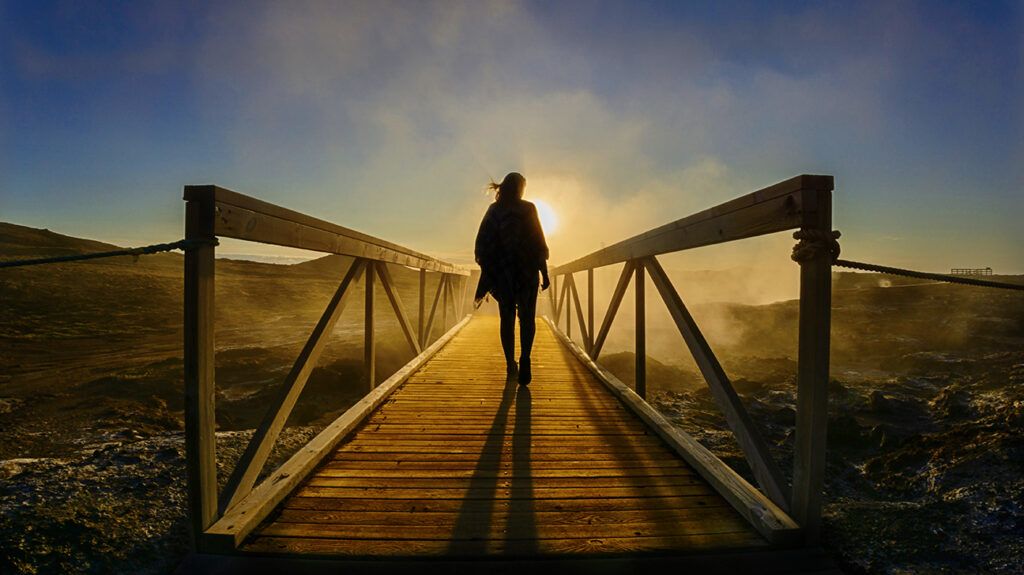 person standing on a bridge at sunrise, symbolic of empowerment