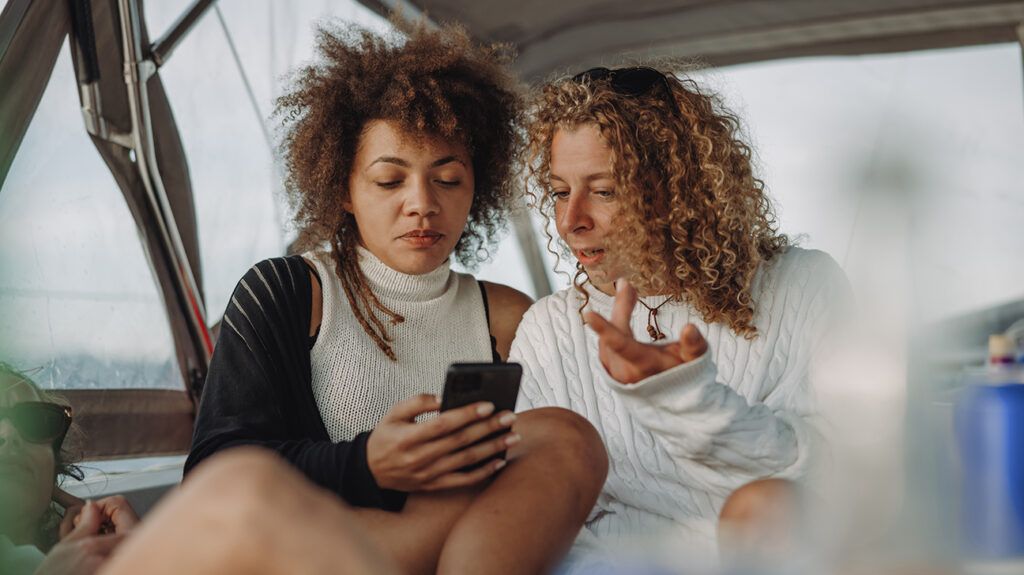 2 women looking at social media and comparing with an acquaintance